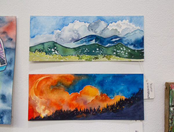 Two horizontal watercolor paintings feature a mountain landscape and a forest fire, respectively