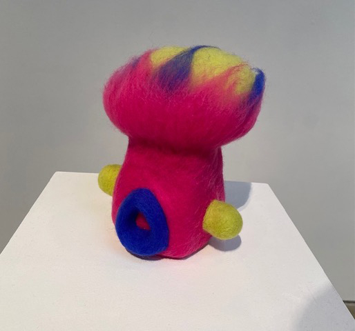 Installation photo of a brightly colored stuffed creature