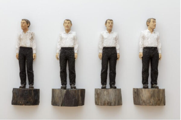 Sculpture of four male figures wearing white button down shirts and black slacks