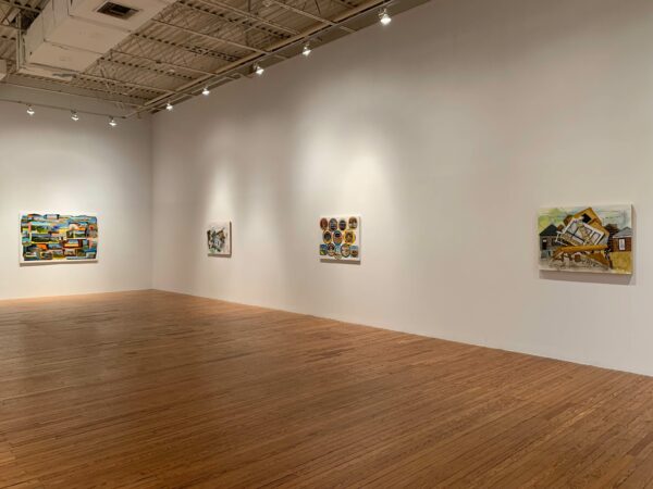 A photo of four paintings hung on the wall of a gallery. The gallery has wooden floors and white walls.