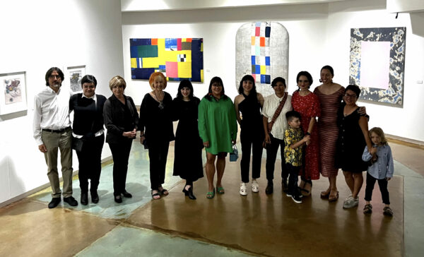 Artists, curator, and director posing for a group photo in an exhibition