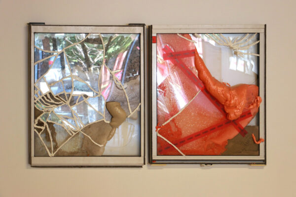 A diptych by Justin Sterling featuring two broken windows. Each window has insulation foam, dirt and gravel on it and tape and caulking has been used to repair the broken glass.