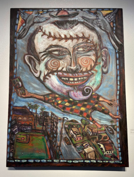 Painting of a figure with the face of a baseball floating above a city-scape