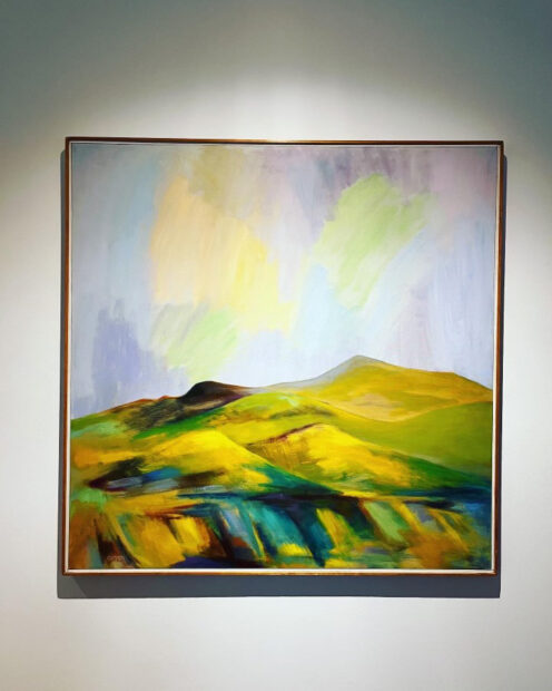 A painting featuring a green, hilly landscape.