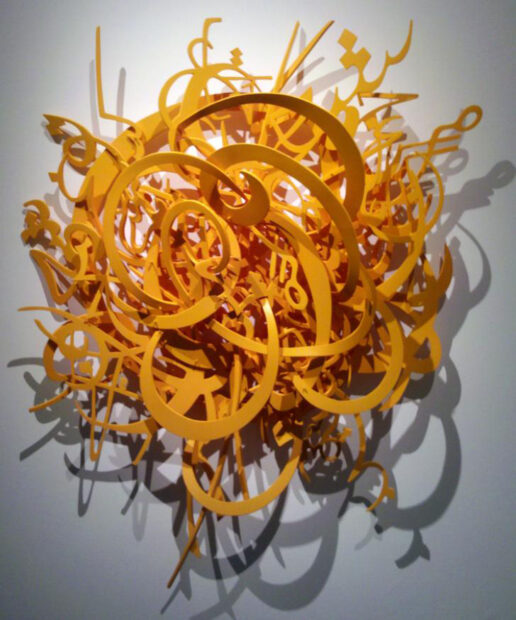 A cluster of yellow words and letters hanging on a white wall