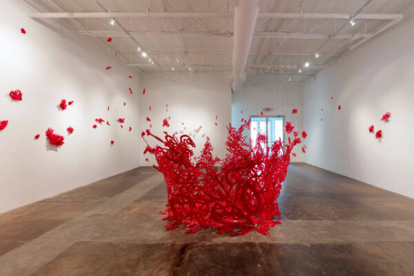 Image of a red sculpture installed to look like it is exploding in the space