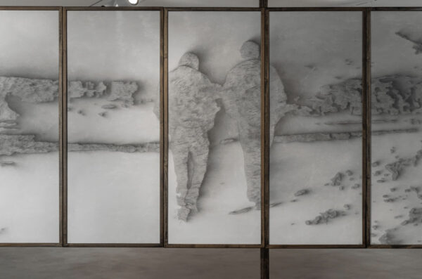 Installation view of two figures walking in a landscape