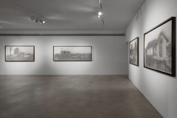 Installation view of framed works on paper hanging on a white wall