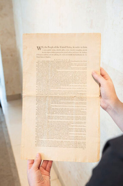 Photograph of someone holding the first edition of the U.S. Constitution