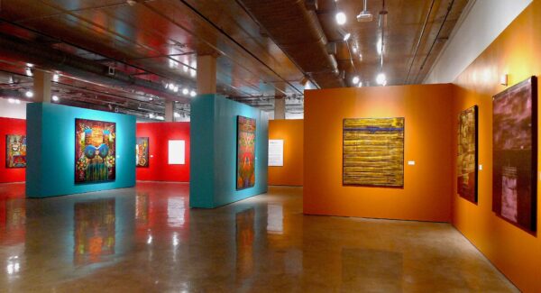 Installation view of large scale works on yellow, turquoise and red walls