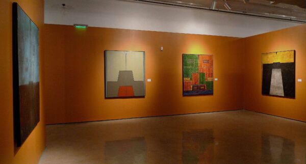 Installation image of large scale paintings on an orange wall