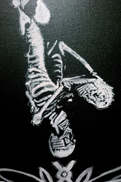 Detail of a human skeleton painted agains a black wall