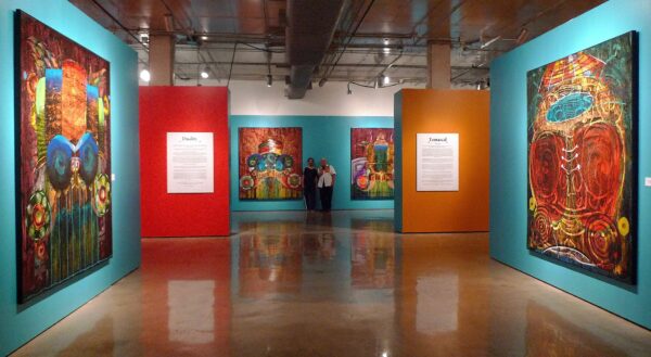 Installation view of large scale paintings on turquoise, orange, and red walls