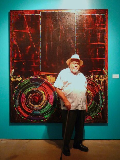 Photo of Dudley Brooks in front of a painting on a turquoise wall