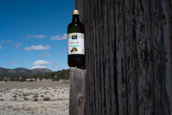 Photo of olive oil in a bottle on top of a fence post
