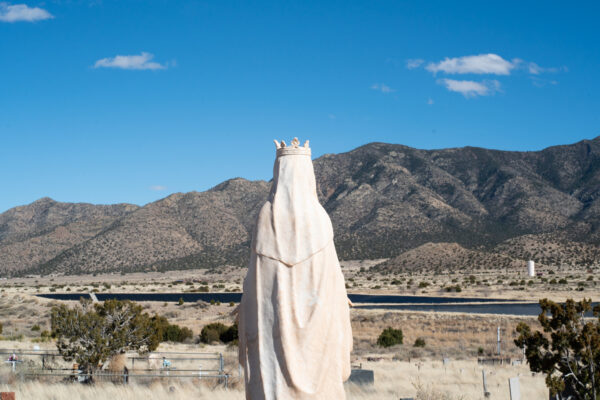 Photo of the back a sculpture of a saint in a desert landscape