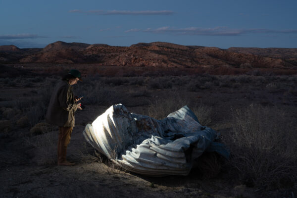 Photo of the author standing above detritus on the side of the road in a desert landscape