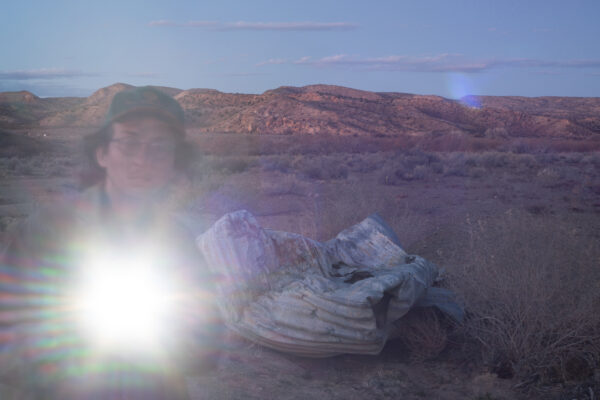 Photo of the author with detritus on the side of the road in a desert landscape