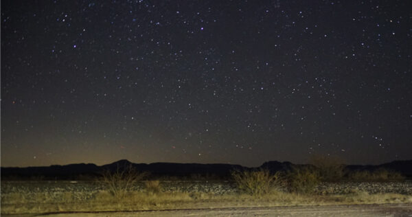 A night time photograph of a distant horizon with stars filling the sky.