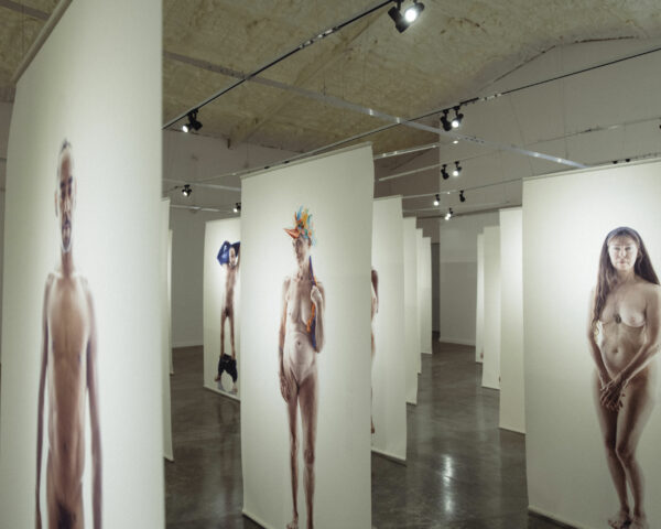 Installation image of large scale nude figures printed on banners in a gallery space