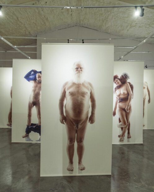 Installation image of large scale nude figures printed on banners in a gallery space