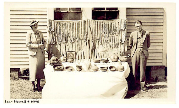 Two people standing on opposite ends of a table selling antiquities from Spiro