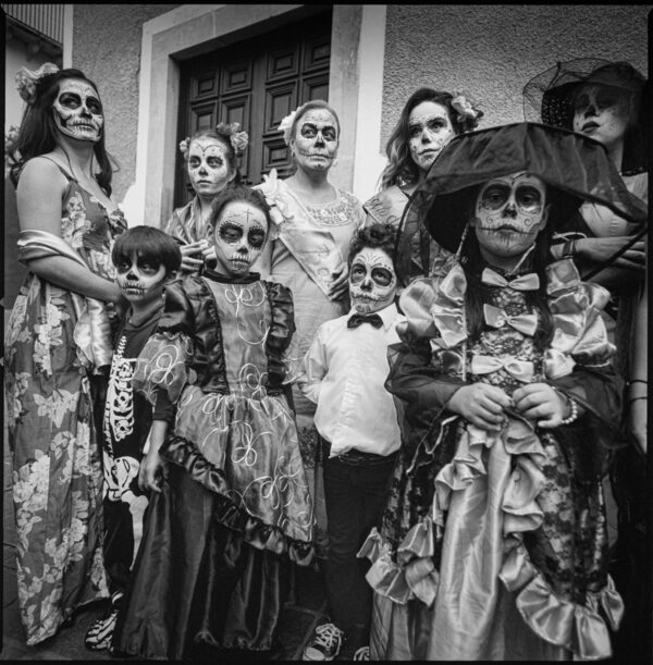 Black and white photograph of a group of people wearing costumes and day of the dead skull-like facepaint.
