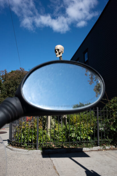 Photo of a skull popping up over a rear view mirror of a car