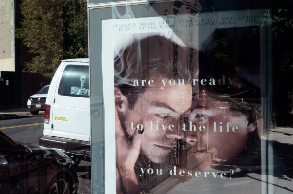 A Skeleton looking out the rear window of a van next to a promo of a film