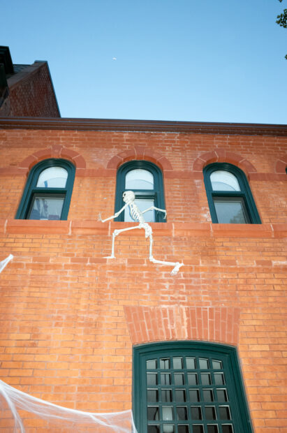 A skeleton scaling a brick wall