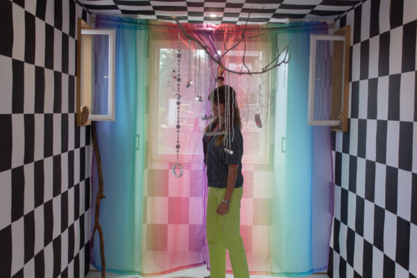 Casey Callahan reaches up to adjust a mobile inside of her exhibition in Omaha.