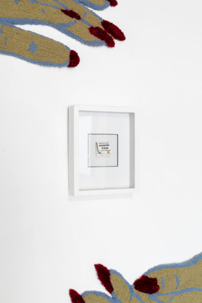 Photo of tufted hands on a wall with a framed matchbook in the center