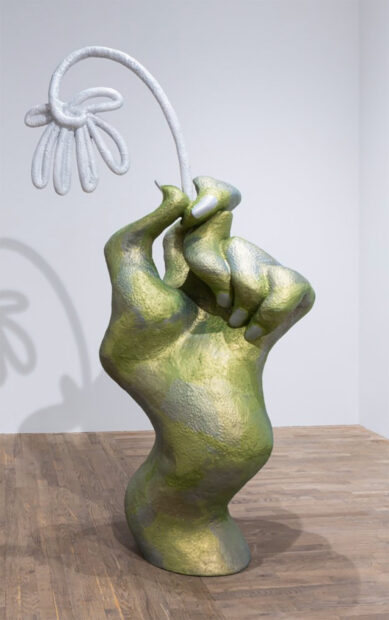 Sculpture of a large warped hand holding a large scale flower