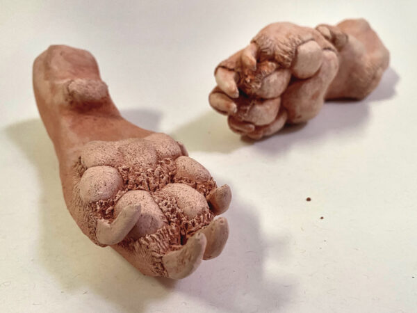 A sculpture of two paws, that looks to be made out of clay.