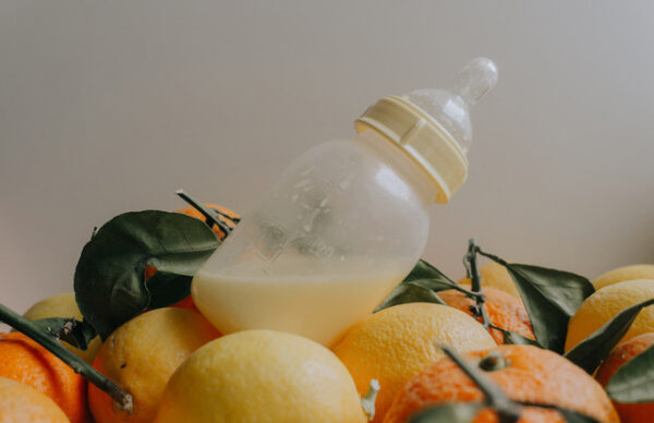 Detail of a bottle sitting in unpeeled oranges