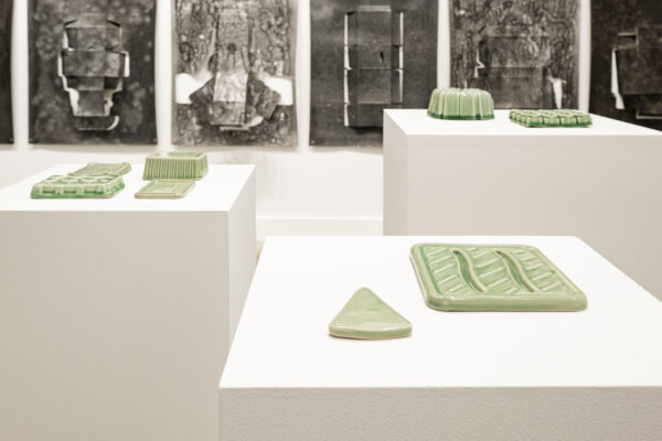Installation view with green ceramic objects and large scale black and white objects