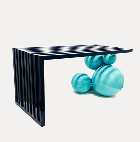 An abstract sculpture by Jessica Bell of five blue spheres attached to a black l-shaped shelf.