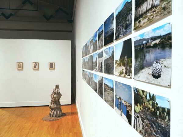 A photo of an art gallery featuring photographs and a sculpture.