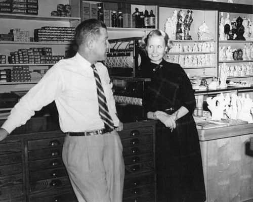 A black and white photograph of a man and woman standing at the counter of an art supply store.