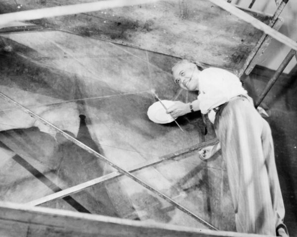A black and white photograph of artist Rufino Tamayo working on the large-scale painting "El Hombre."