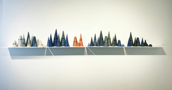 Installation view of ceramic, conical works on a shelf