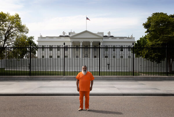 A photo of a man in an orange jumpsuit, standing in front of the White House.