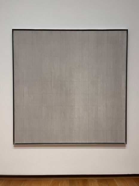 A large square shaped canvas painted by Agnes Martin. The work depicts 216 vertical rectangles.