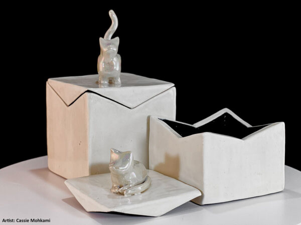Two ceramic boxes with lids made by Artwork by Cassie Mohkami. Each box features a white cat on top of the lid.