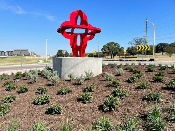 Large red public sculpture in a roundabout