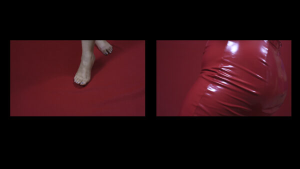 Video still of feet on a red carpet on the left side and a person wearing red leather pant on the right side