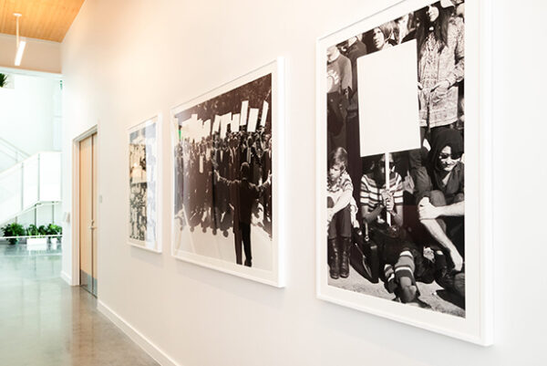 An installation image of three works by Phillip Pyle II. Each is a black and white image of protesters marching in the street.