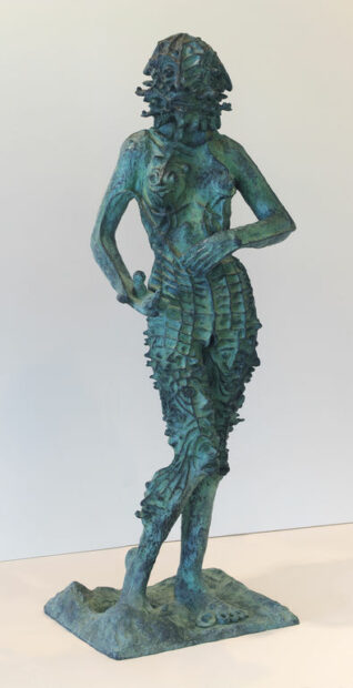 A bronze sculpture by Ho Baron of standing figure that appears to have scales on its hips and legs. 