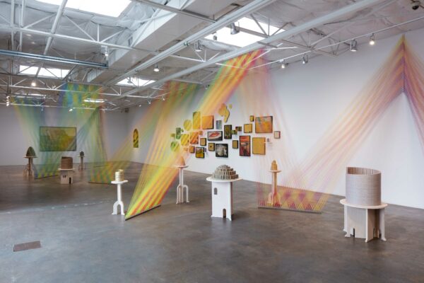 Installation view with string from floor to ceiling and unfinished puzzles