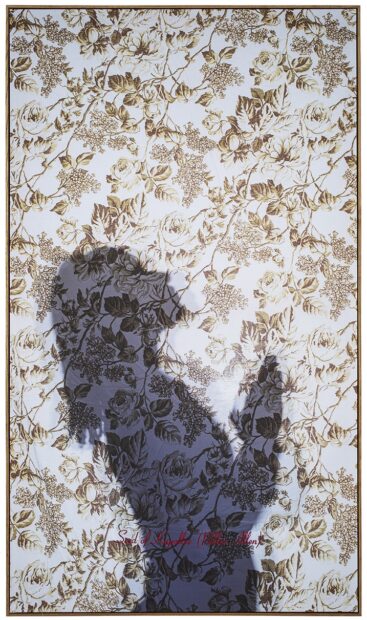 A photograph of a silhouetted figure printed on floral pattern fabric with red embroidery. 